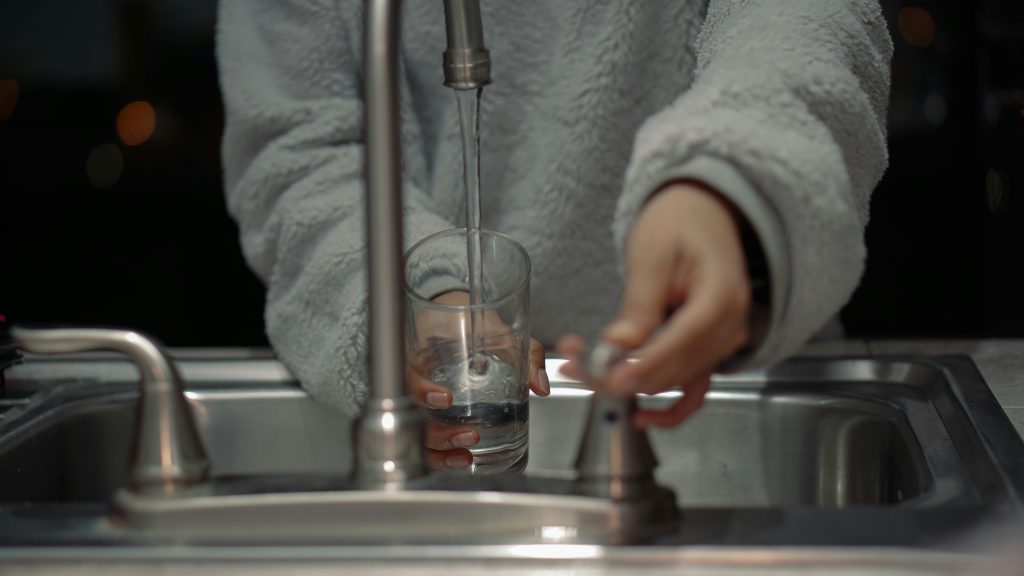 person filling a glass of water from safest water filtration company in central florida