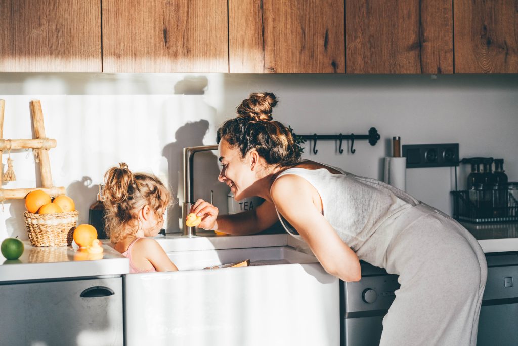 Mother and daughter enjoying bath time in the kitchen sink with filtered Brita Pro water, highlighting safe and clean water for family use.
