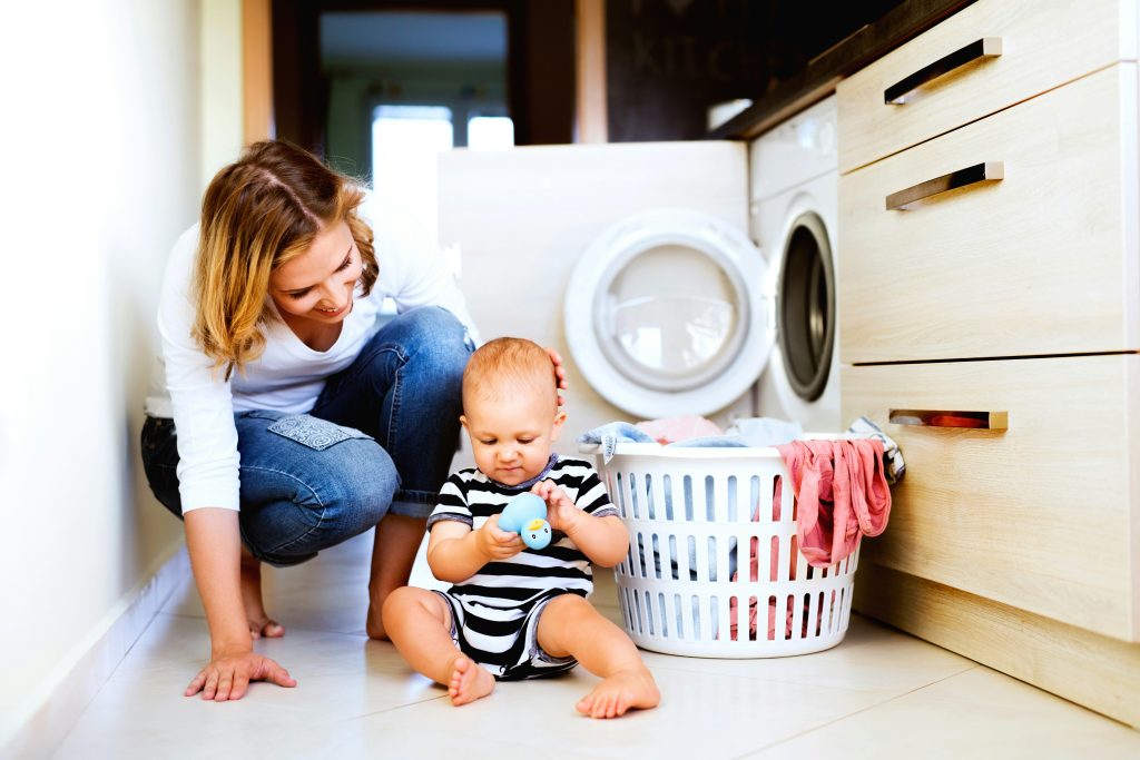 Mother and baby spending time together in the laundry room, emphasizing family care, cleanliness, and Brita Pro filtered water solutions for a healthier home environment.
