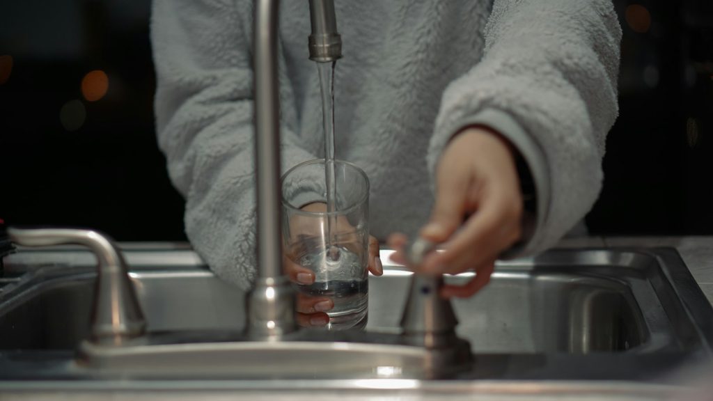 Homeowner filling a glass with tap water at a kitchen sink